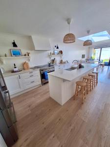 a kitchen with white cabinets and a kitchen island with bar stools at Bungalow by the Sea, Moelfre in Moelfre