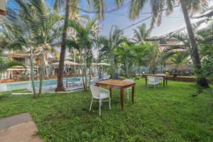 a table and chairs in the grass near a pool at Echor La Blanca Resort Mandrem Goa in Mandrem