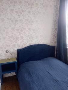 a bedroom with a blue bed and a side table at Le Clos doré Baie de Somme in Abbeville