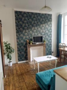 a living room with a table and a tv on a wall at Le Clos doré Baie de Somme in Abbeville