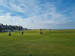 a group of people standing on a field of grass at Sandstones in North Berwick