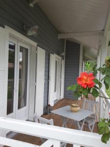 a table on a porch with a flower in a vase at Maison proche du Bassin d'Arcachon in Salles