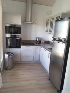 a kitchen with white cabinets and a stainless steel refrigerator at Maison proche du Bassin d'Arcachon in Salles +1 photo