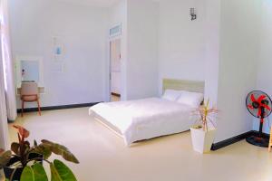 a white bedroom with a bed and a plant at LƯNG CHỪNG Home in Xuan An