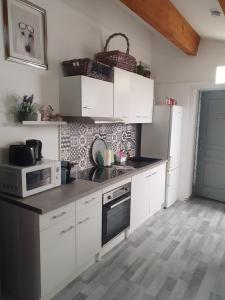 a kitchen with white cabinets and a microwave at Le jardin secret in Uchaud