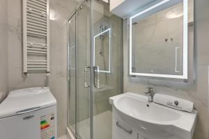 une salle de bain blanche avec un lavabo et une douche dans l'établissement Central Apartment Gdynia by Lion Apartments, à Gdynia