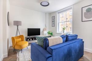 a living room with a blue couch and a yellow chair at BnBNova - 1BR - St Paul's & Barbican in London +16 photos