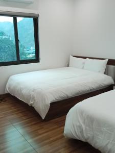 two beds in a room with a window at Zon homestay & restaurant in Cat Ba