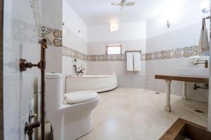 a bathroom with a toilet and a tub and a sink at Hotel Chandrawati Palace in Ābu Road