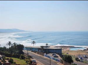 a view of the beach and the ocean with cars parked at Peacehaven's Top Floor Gem 703 in Scottburgh
