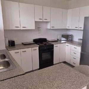 a kitchen with white cabinets and a black stove at Peacehaven's Top Floor Gem 703 in Scottburgh