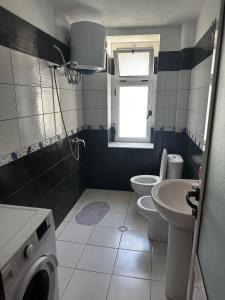a bathroom with a toilet sink and a washing machine at Zoto Guest House in Përmet