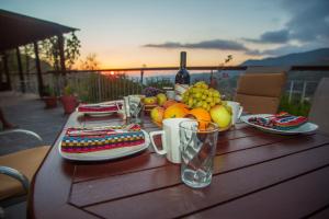 a wooden table with a plate of fruit and a bottle of wine at VILLa EUPHEMIA in Kato Platres