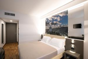 a bedroom with a white bed with a picture on the wall at Hotel Federico II in LʼAquila +66 photos
