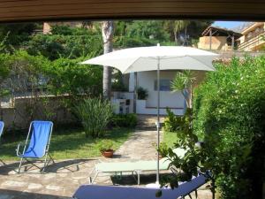 a patio with a table and an umbrella and chairs at Scopello Beach in Scopello