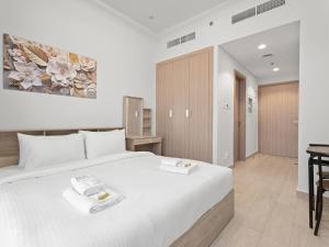 una camera da letto con un grande letto bianco e una scrivania di Homely Bliss Studio in Azizi Riviera a Dubai