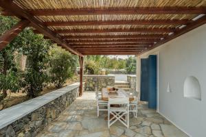 un patio con mesa y sillas bajo una pérgola de madera en Villa Orea Beachfront by Mykonos Mood, en Kalafatis
