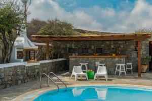 Un patio trasero con piscina y bar. en Villa Orea Beachfront by Mykonos Mood, en Kalafatis
