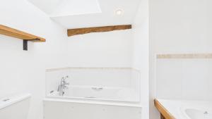 a white bathroom with a tub and a sink at The Cote is a stunning rural barn beach 3 miles in Haven Street +22 photos