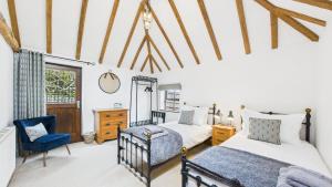 a bedroom with two beds and a chair at The Cote is a stunning rural barn beach 3 miles in Haven Street