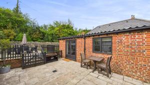 a brick house with a table and chairs on a patio at The Cote is a stunning rural barn beach 3 miles in Haven Street