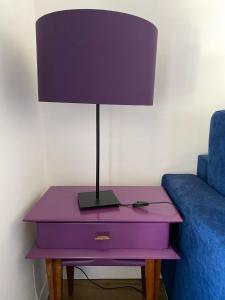 une table violette avec une lampe dessus à côté d'un canapé dans l'établissement Emeraude, à Saint-Raphaël