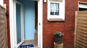 a door to a brick house with a potted plant at Ferienwohnung Seewiefke in Holtgast