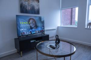 a living room with a glass table and a tv at Hive Apartment Manchester in Manchester