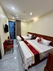 Una habitación de hotel con dos camas y un escritorio. en Hotel Hải Âu, en Sầm Sơn