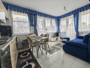 a living room with blue curtains and a blue couch at Apartman Roberto in Hajdúszoboszló