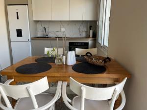 a kitchen with a wooden table and white chairs at MZ apartment in Néa Péramos