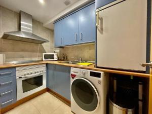 a kitchen with blue cabinets and a washing machine at Beach Panorama in Marbella