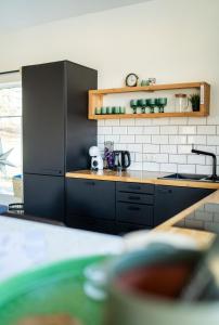 a kitchen with black cabinets and a counter top at PLŪSME Restart House in Lielstraupe