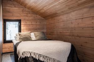 a bedroom with a bed in a wooden wall at Villa Draivi B By Hilla Villas - 3BR and alcove in Kittilä