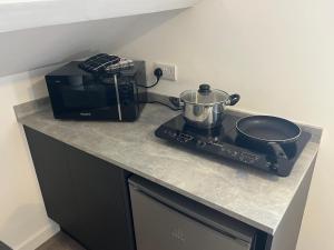 eine Küchentheke mit einem Topf auf einem Herd in der Unterkunft Loft studio apartment, BL, Town Centre, Secure gated parking option, Modern, fresh and spacious living, Netflix ready TV, Wifi in Wellingborough + 4 Fotos