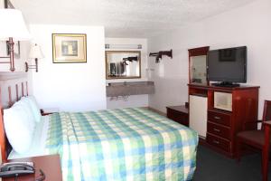 Habitación de hotel con cama y TV de pantalla plana. en Crown Inn, en Denver City