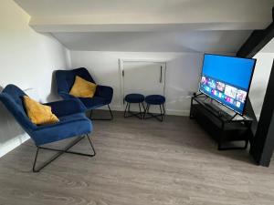 ein Wohnzimmer mit zwei Stühlen und einem Flachbildfernseher in der Unterkunft Loft studio apartment, BL, Town Centre, Secure gated parking option, Modern, fresh and spacious living, Netflix ready TV, Wifi in Wellingborough