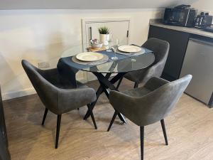 ein Esstisch mit vier Stühlen und einem Glastisch in der Unterkunft Loft studio apartment, BL, Town Centre, Secure gated parking option, Modern, fresh and spacious living, Netflix ready TV, Wifi in Wellingborough