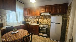 イドラにあるLuljeta's Guest Houseのテーブルと白い冷蔵庫のあるキッチン