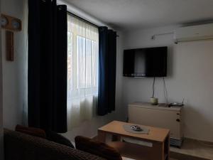 a living room with a tv and a table and a window at Smurf's house in Budva