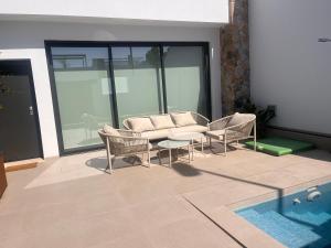 a patio with a couch and chairs and a pool at Villa Buba in Pilar de la Horadada