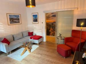 a living room with a couch and a red chair at Ferienwohnung Lucy - Moderne Ferienwohnung mit kostenlosem Parkplatz, Terrasse, nahe Bad Schandau und Malerweg in Bad Schandau