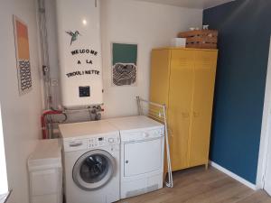 a laundry room with a washing machine and a yellow cabinet at La Troulinette in Esneux