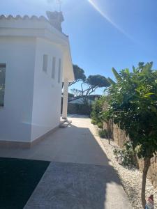 a white building with a walkway next to some trees at Chalet Real Santé in Novo Sancti Petri