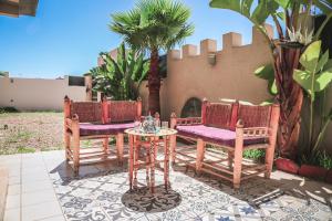 une terrasse avec 2 chaises, une table et un palmier dans l'établissement Villa moderne à 5 min de la plage avec jardin et 3 salons, à Essaouira