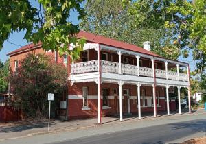 an old red brick building with a white balcony at Honeysuckle Inn - Violet Town in Violet Town