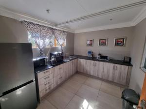 a kitchen with wooden cabinets and a refrigerator at La Cordier in Kroonstad