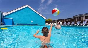 a boy playing with a beach ball in a swimming pool at Moonstone Hayling Island Holiday Park in South Hayling