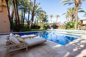 een zwembad met een chaise longue naast een villa bij Villa les Palmiers in Marrakesh