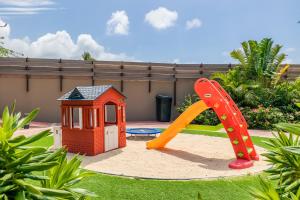 un parque infantil con tobogán y una casa de juegos en Bocobay Porta al Sole - Luxury Condos 5 min Walk to Ritz and Palm Beach, en Palm-Eagle Beach